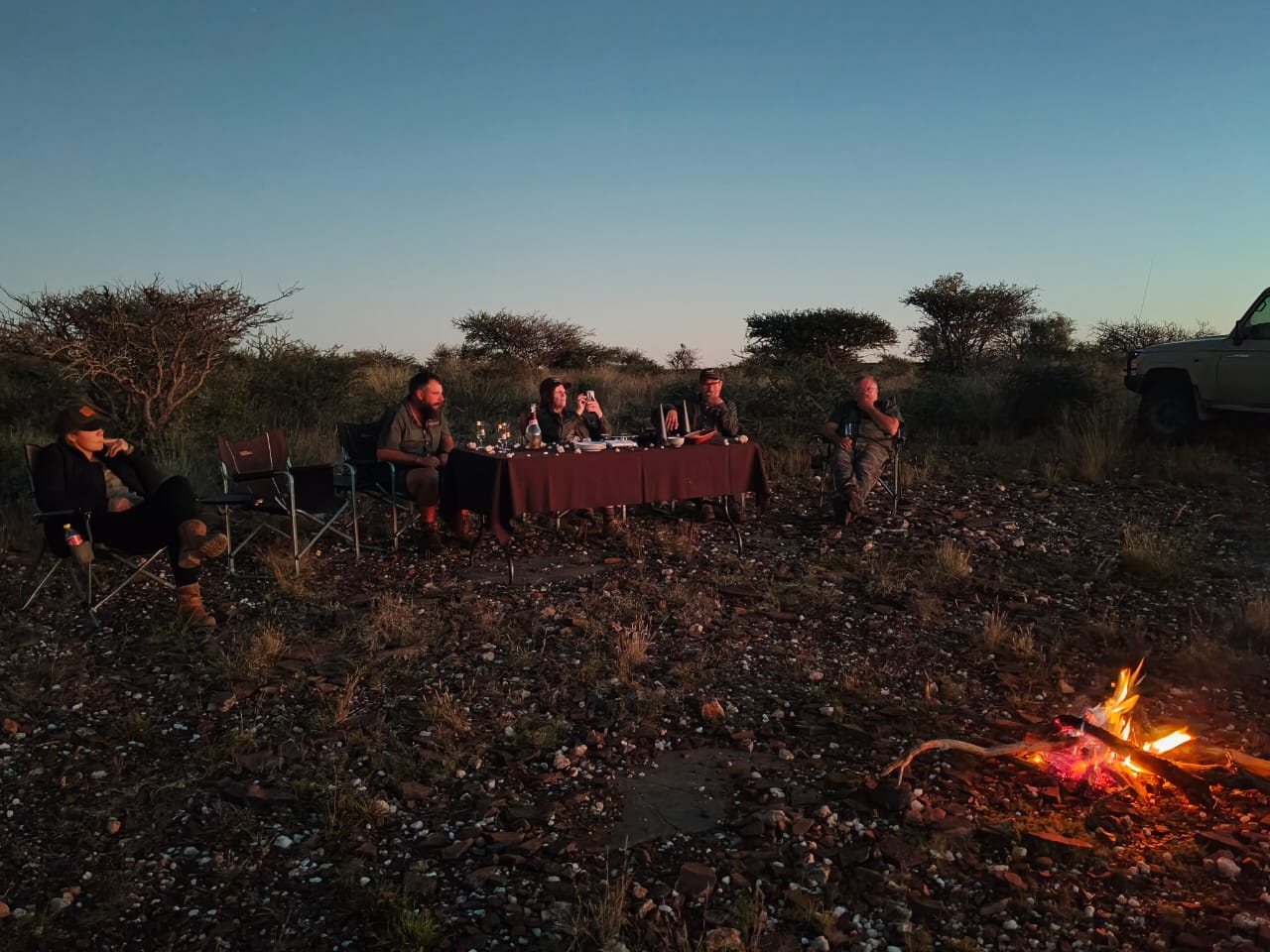 Guests at the table and fire at a bush sundowner