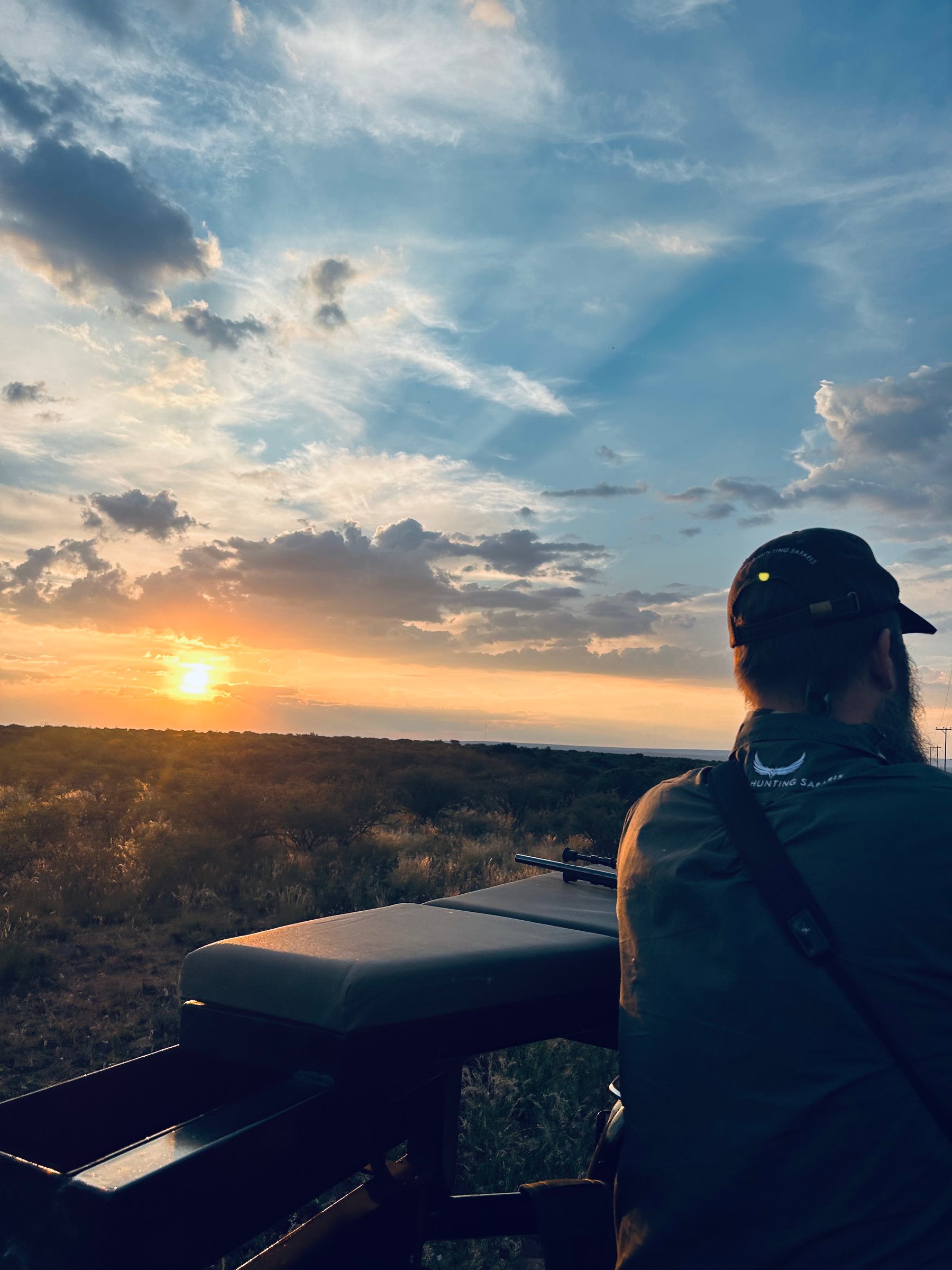 A guide watches the sun go down from the game vehicle