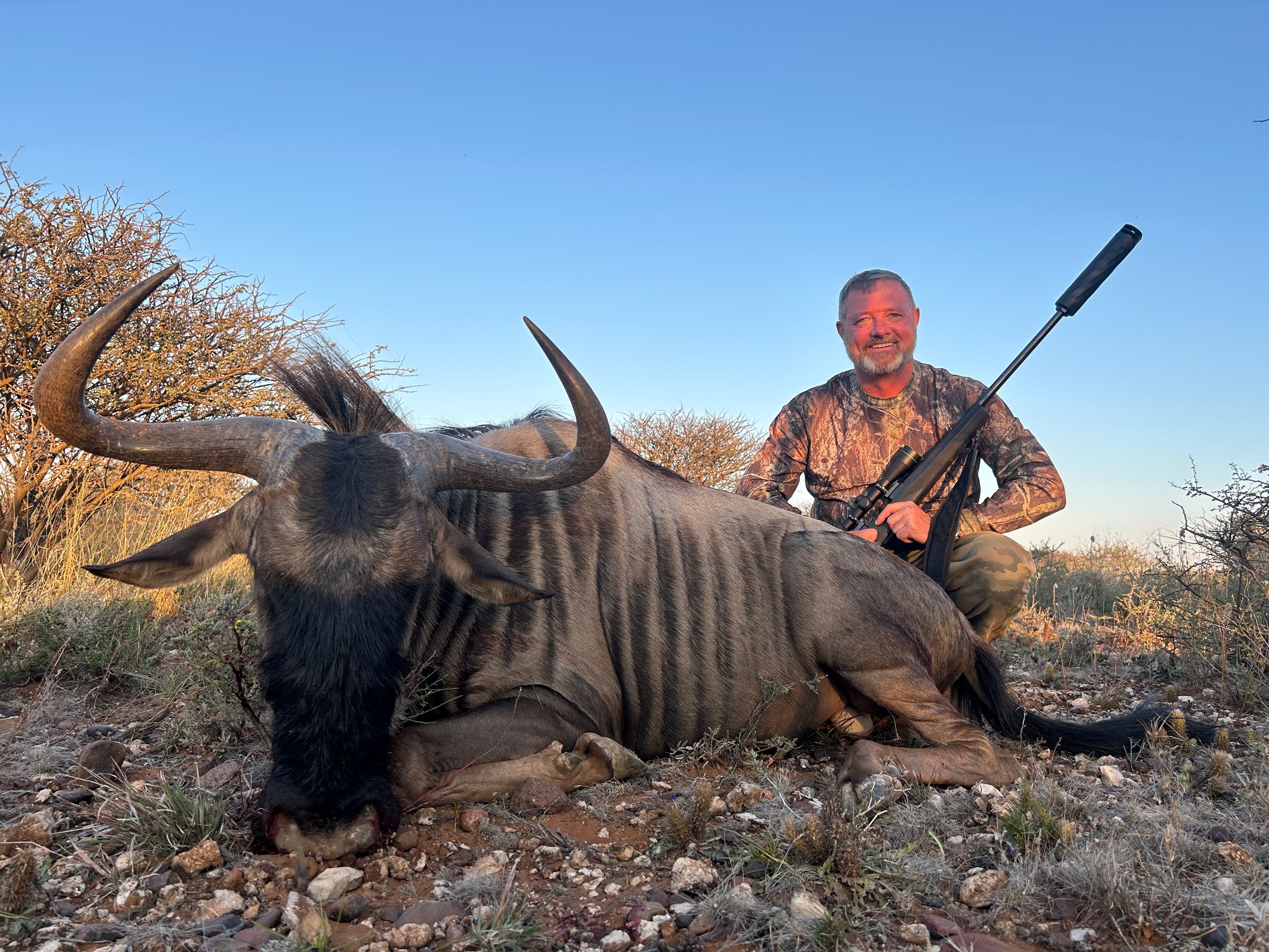 A hunter with a blue wildebeest in the evening light