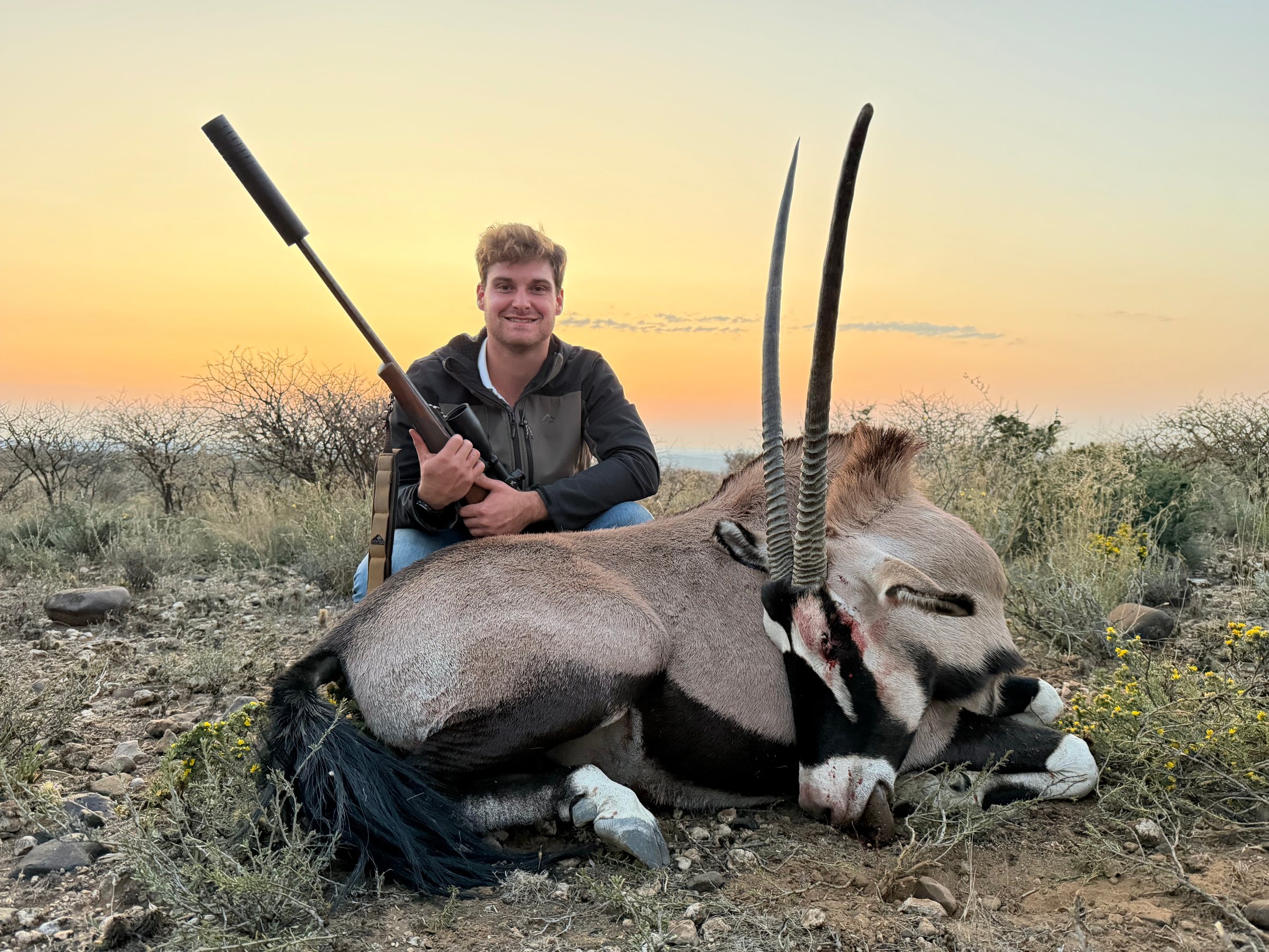 A young hunter with his gemsbok at sunset