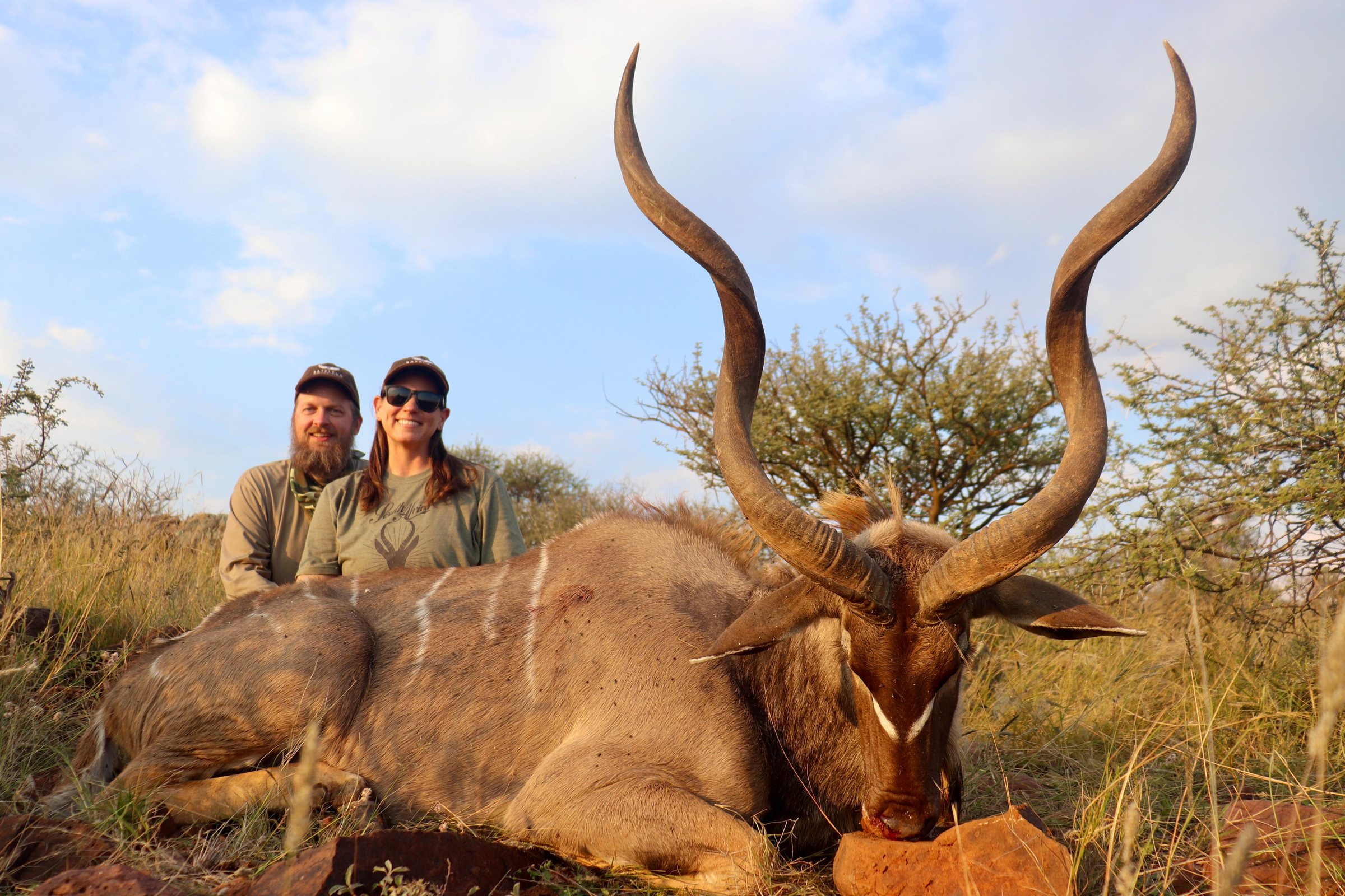 Two hunters with a kudu bull in the late afternoon light