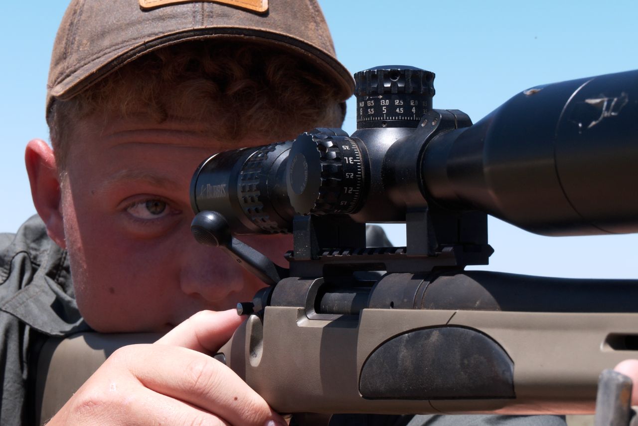 A hunter sights through his rifle scope