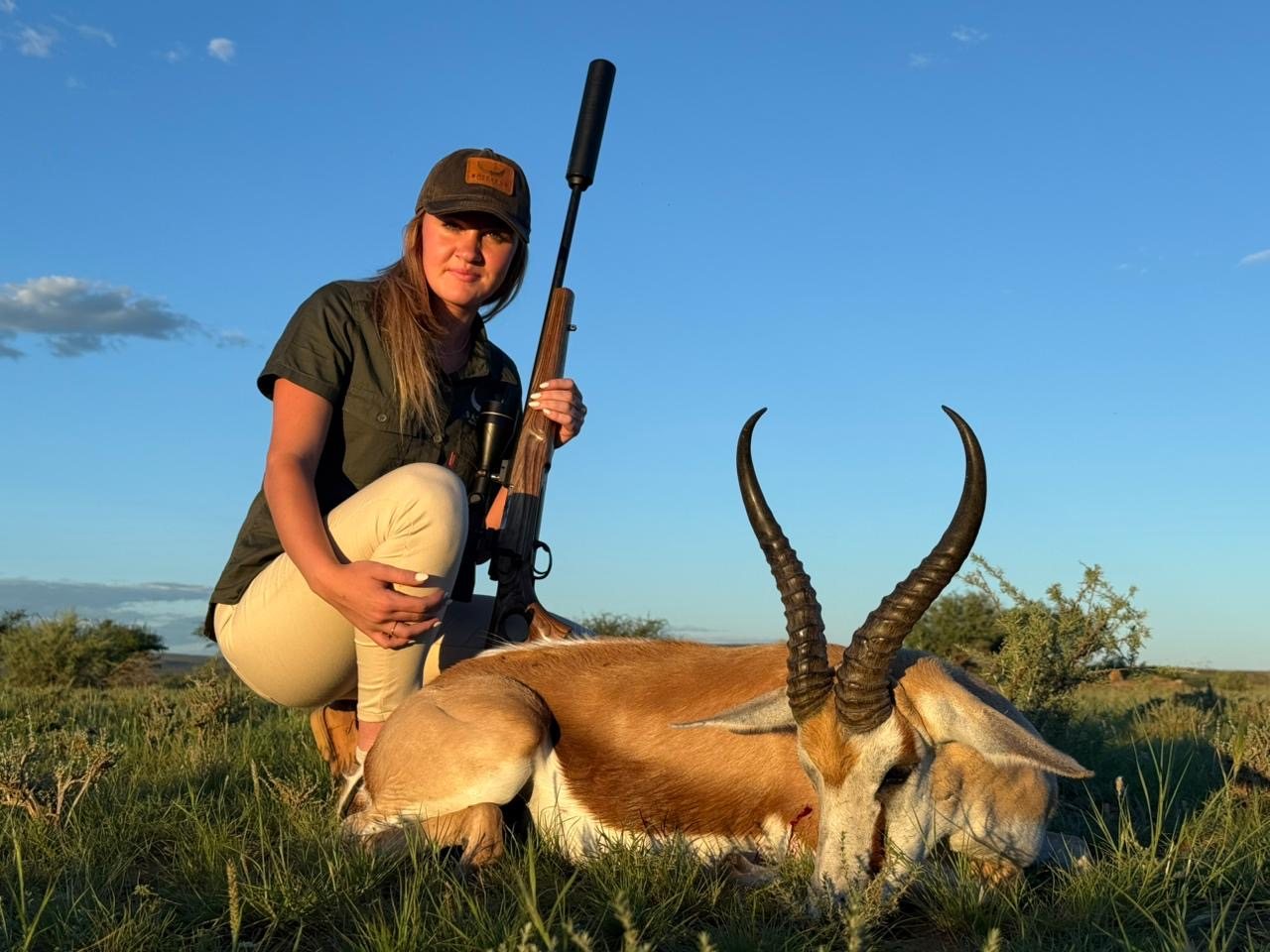 A huntress kneels beside her springbok