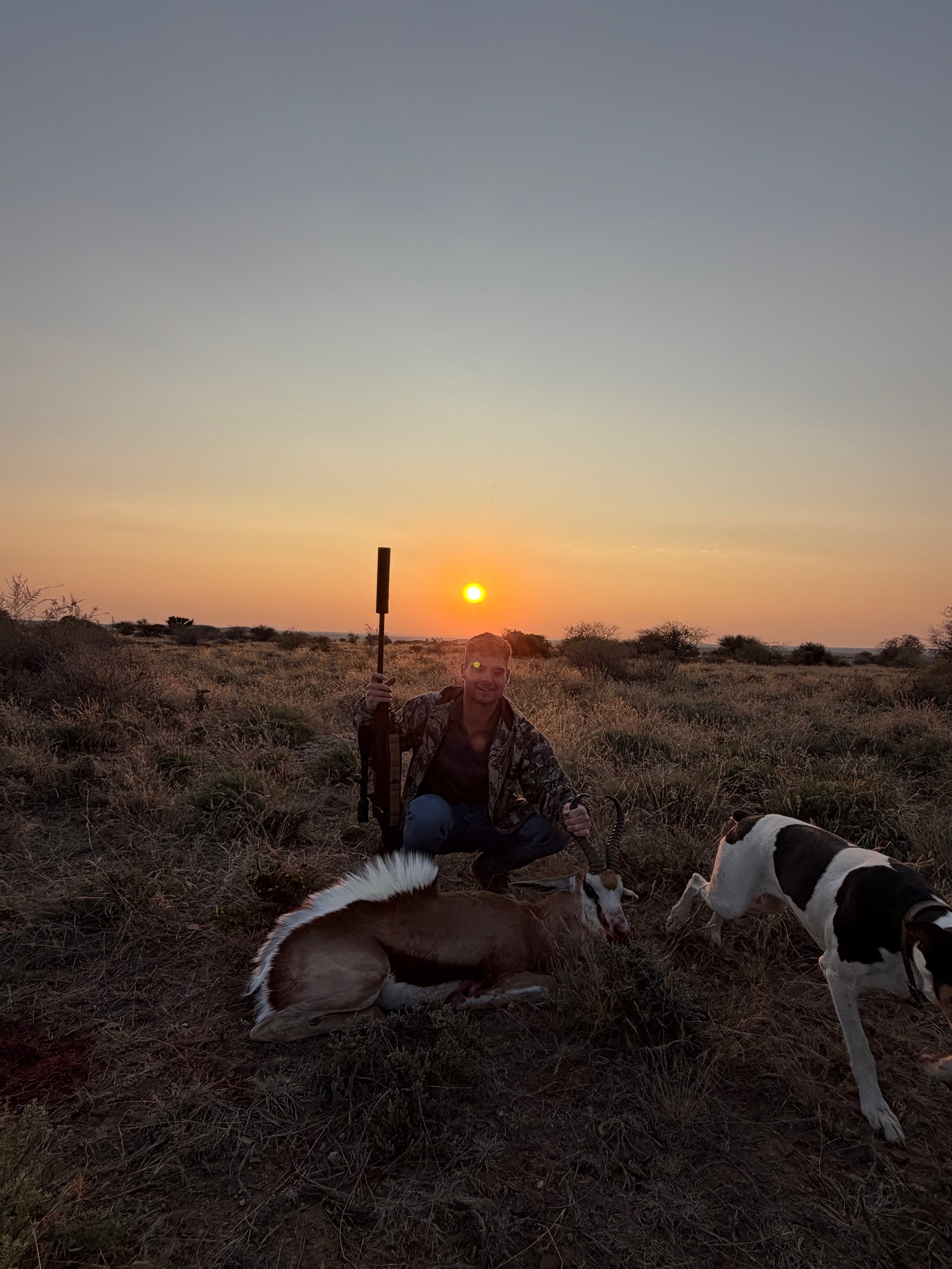 A hunter, his springbok and a tracking dog as the sun sets