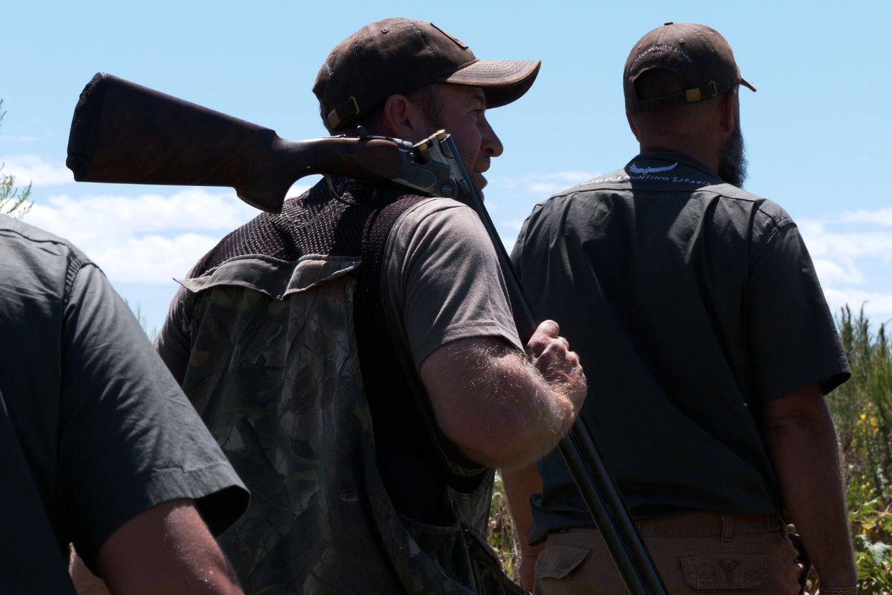 Bateleur hunters walk out together, rifle on the shoulder