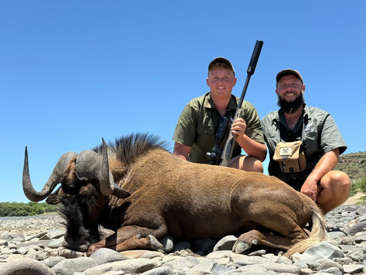 Two hunters with a black wildebeest
