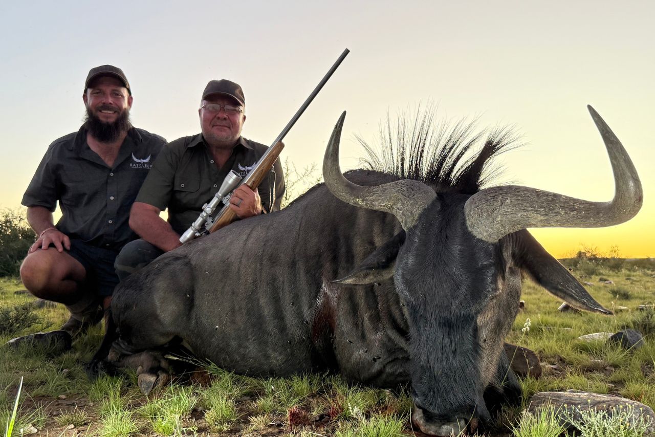 Two hunters with a wildebeest at sunset