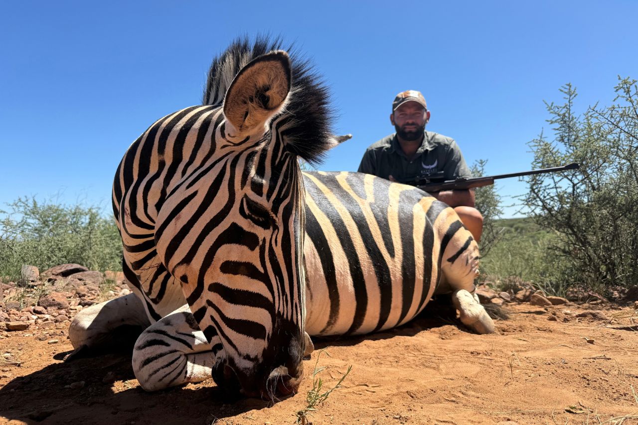 A hunter with a zebra trophy