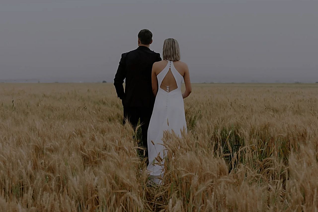 A couple walks through a golden field