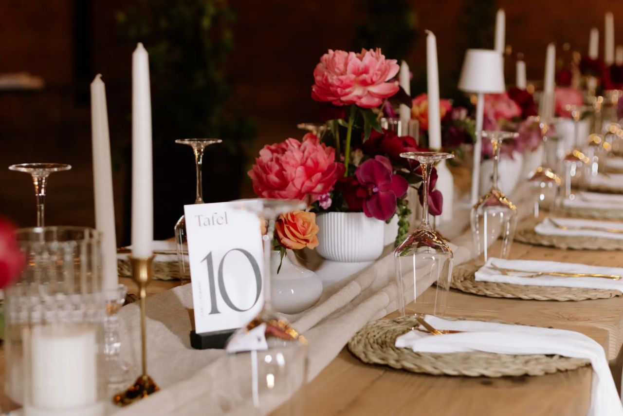 A long table set with candles and peonies